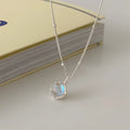Women's sterling silver curb chain necklace with a geometric ornamental stone pendant on a grey background.