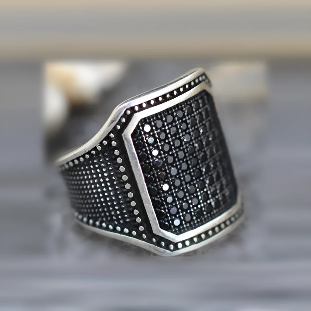 Black alloy ring with copper inlay and zircon accents on a finger, showing European and American styling.