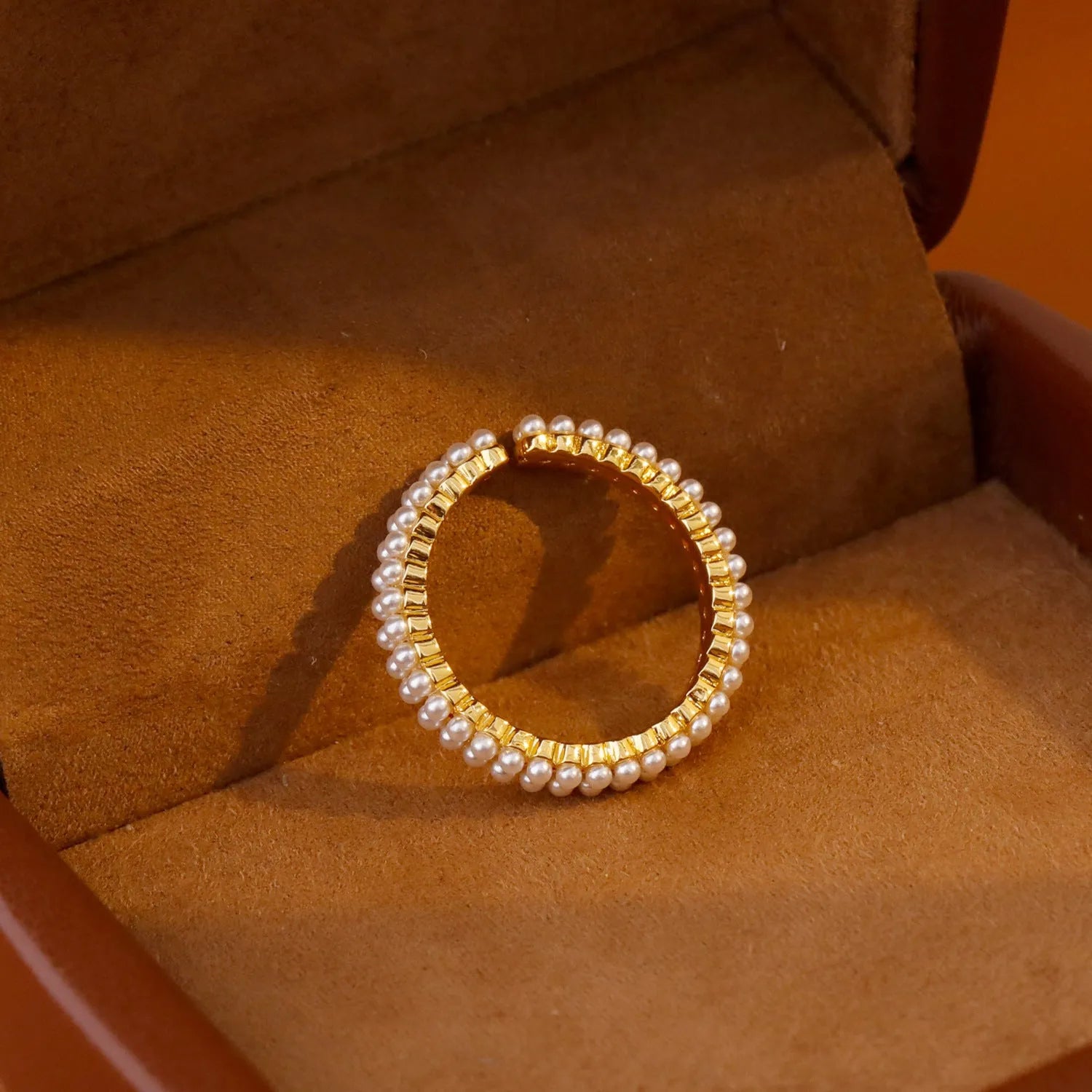 Gold geometric ring with open mouth design and pearl elements on female hand