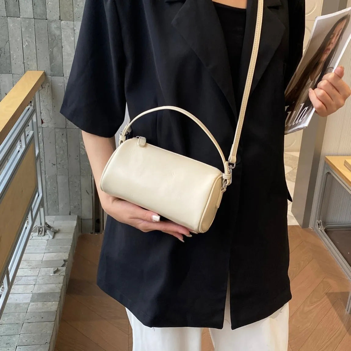 Soft genuine leather cylindrical crossbody bag for mobile phones in brown colour with visible stitching.