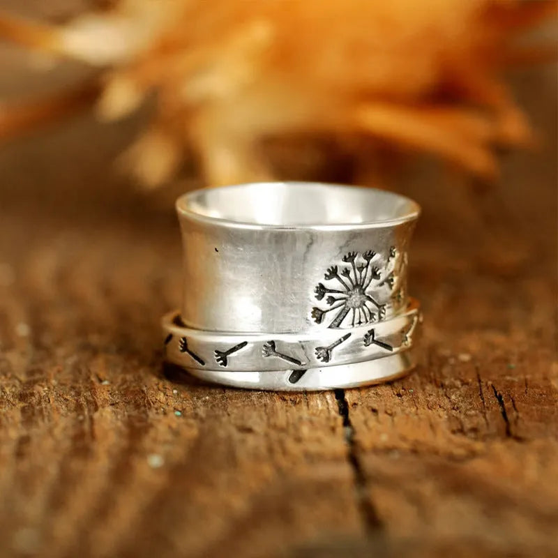 Silver coloured rotating flower fashion ring on a hand, showing adjustable band and floral design.