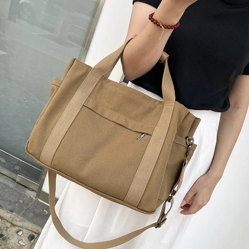Large horizontal square canvas tote bag in army green with visible sewing lines and open zipper sides.