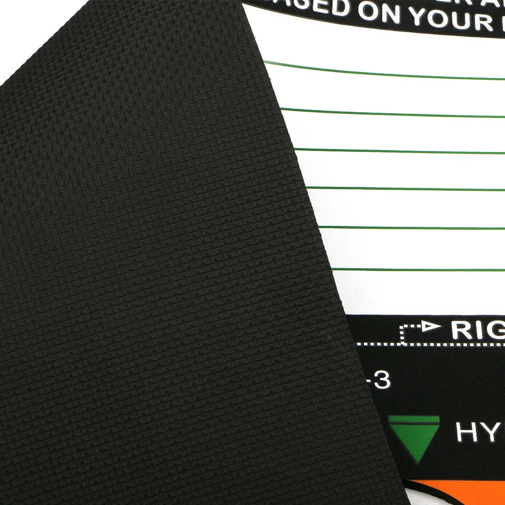 Black neoprene golf swing posture aid mat on grass, showing its compact size and alignment markings.