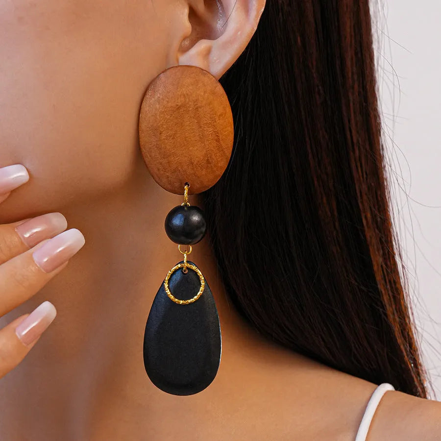 Brown and black wooden elliptical earrings with silver needle details on retro background
