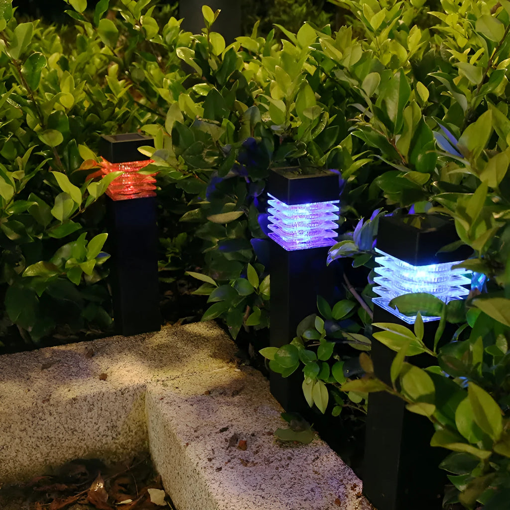 White cuboid solar lawn ground lamp staked in garden soil with solar panel on top