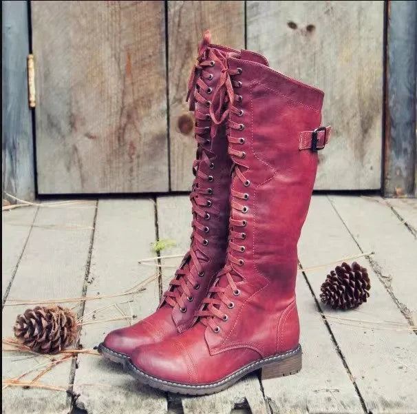 A pair of black chunky heel high leg boots with a round toe on a solid background.