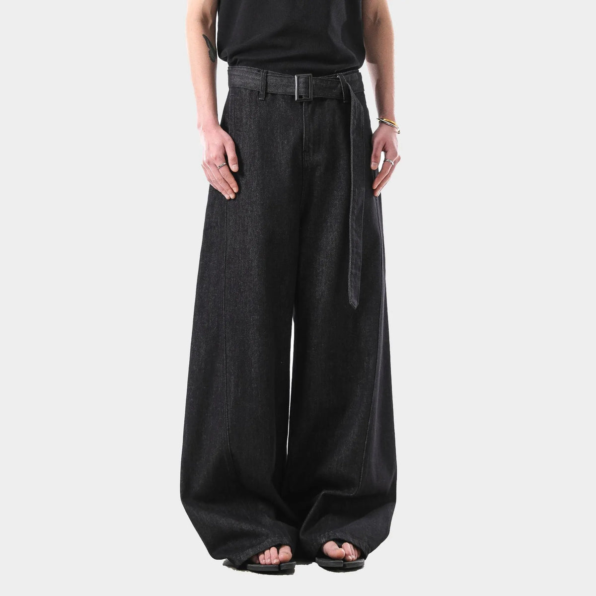 Black high-waist straight-leg jeans with gold details on a denim background.