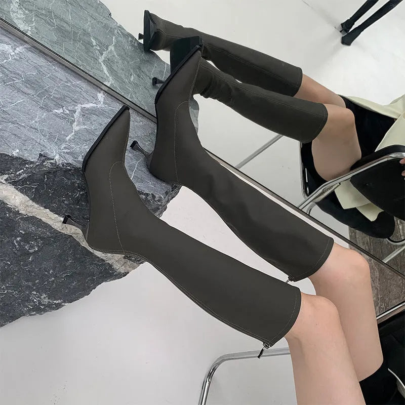 Black pointed toe women's boots with a back zipper and a stiletto heel.