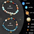 Set of two natural stone beaded bracelets with zodiac sign designs on a wooden surface.