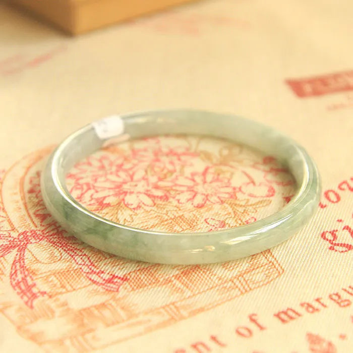 Green geometric jade waxy bracelet with 10mm diameter on a wrist.