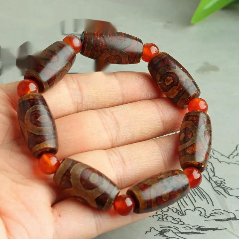 Distressed agate Tibetan bead bracelet with three-eye motifs and polished finish.
