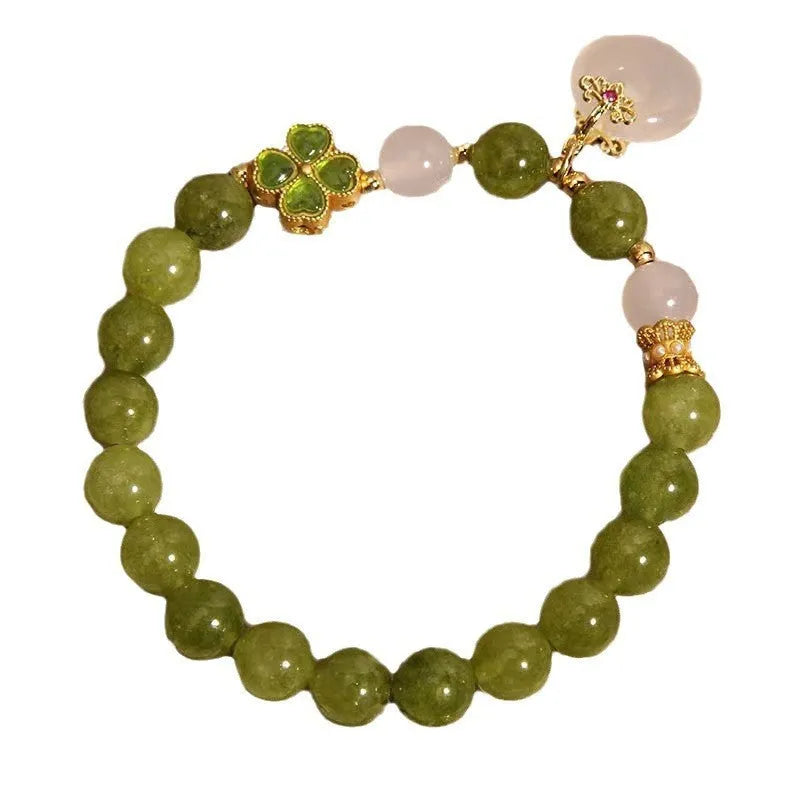Women's green tourmaline bracelet with four-leaf clover safety buckle on a wrist.
