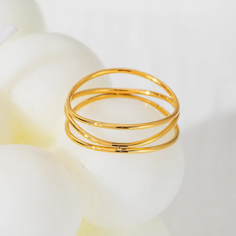 Gold-coloured titanium steel geometric ring with a three-layer coil design on a plain background.