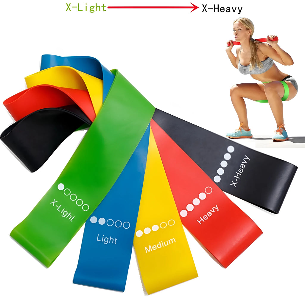 Five colour-coded yoga tension straps for resistance training laid flat showing green, blue, yellow, red, and black options