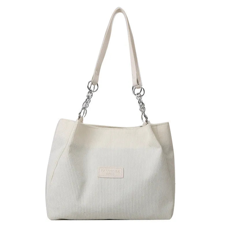 Corduroy one-shoulder tote handbag in a horizontal square shape with a three-dimensional outer pocket.
