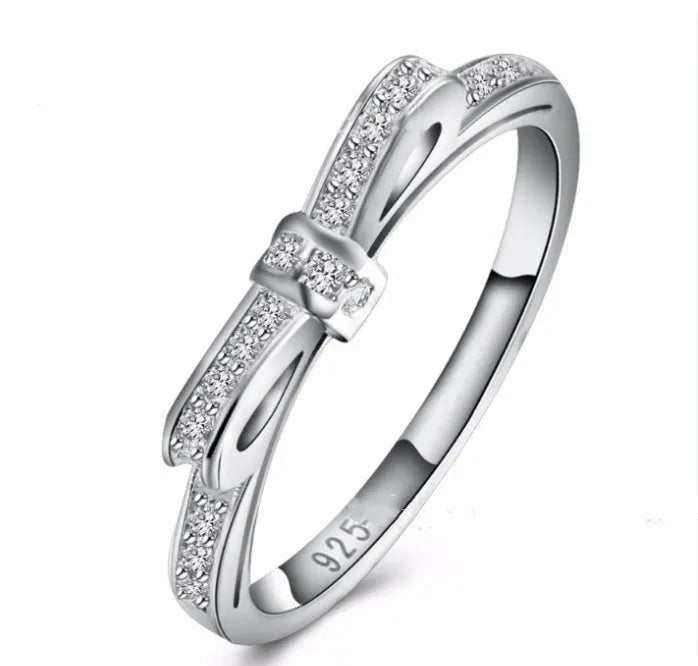 Silver-coloured bow-shaped ring with clear rhinestone embellishments on a white background