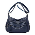 Large blue women's crossbody shoulder bag with a zipper and soft handle, shown with internal organiser pockets.