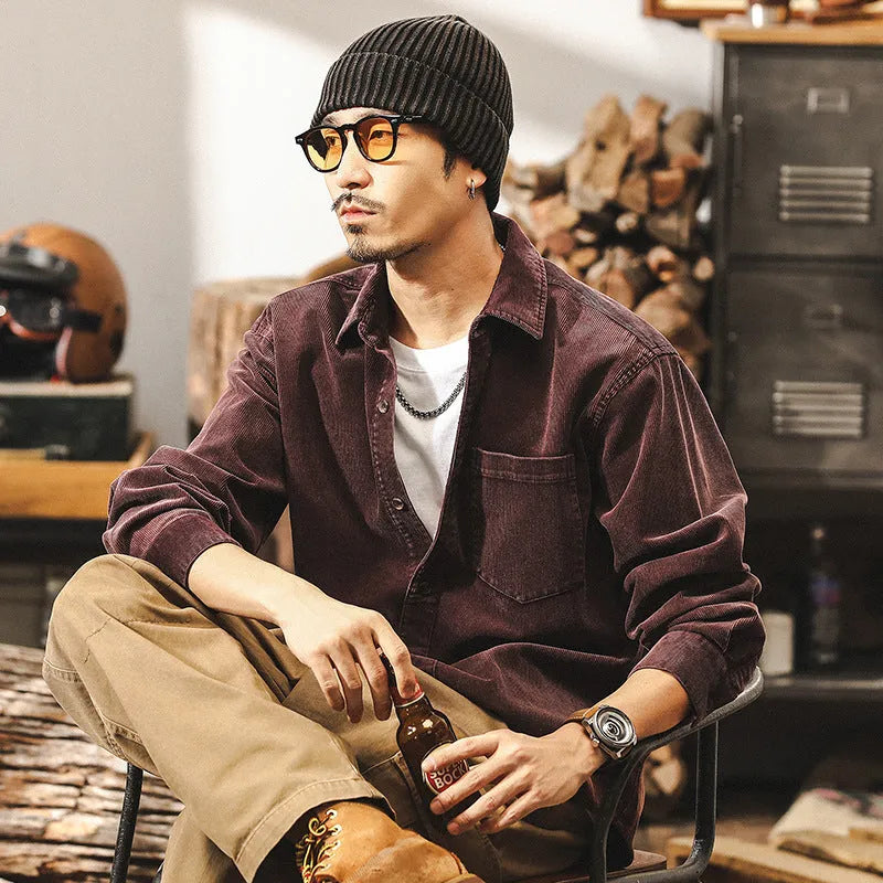 Men's black loose-fit corduroy shirt jacket with long sleeves on a hanger.