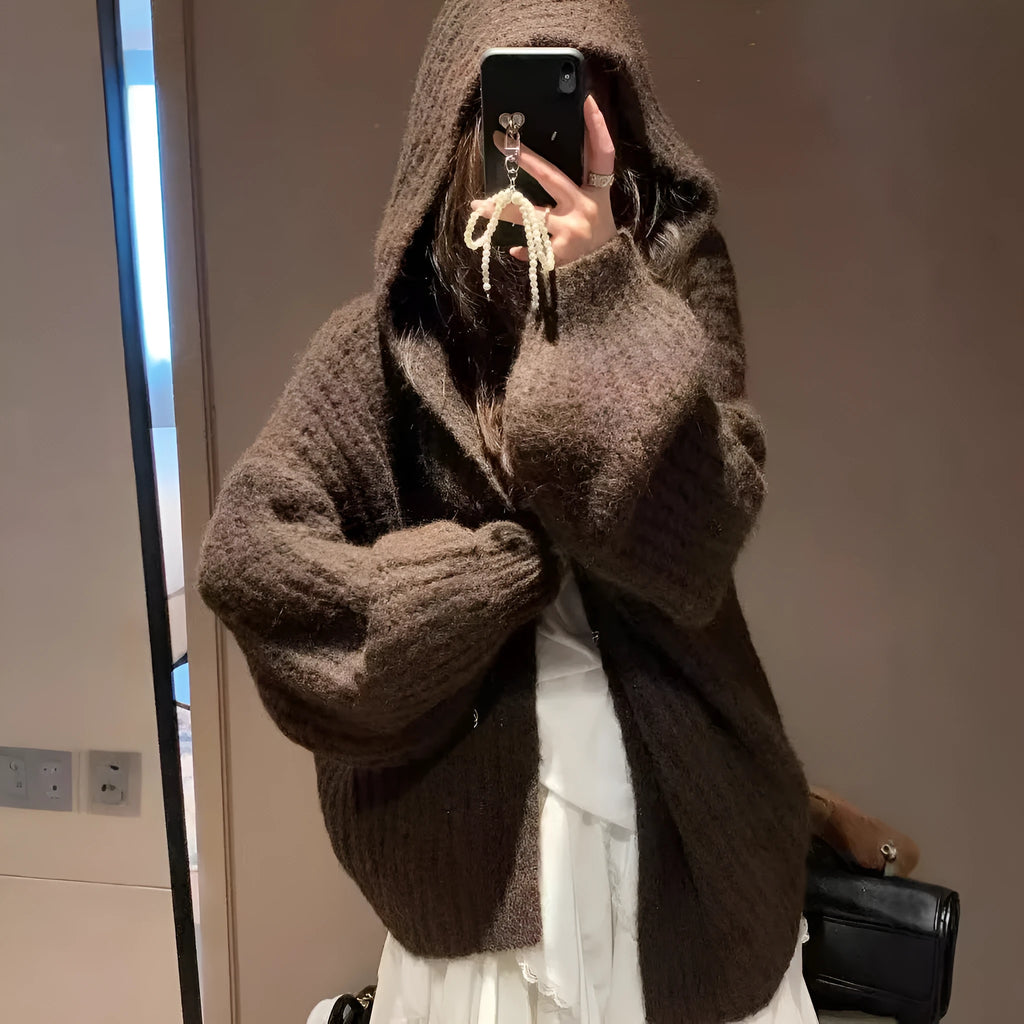 A woman's loose-fit hooded sweater cardigan in a thick fabric, shown in dark grey, brown, and milky white colour options.