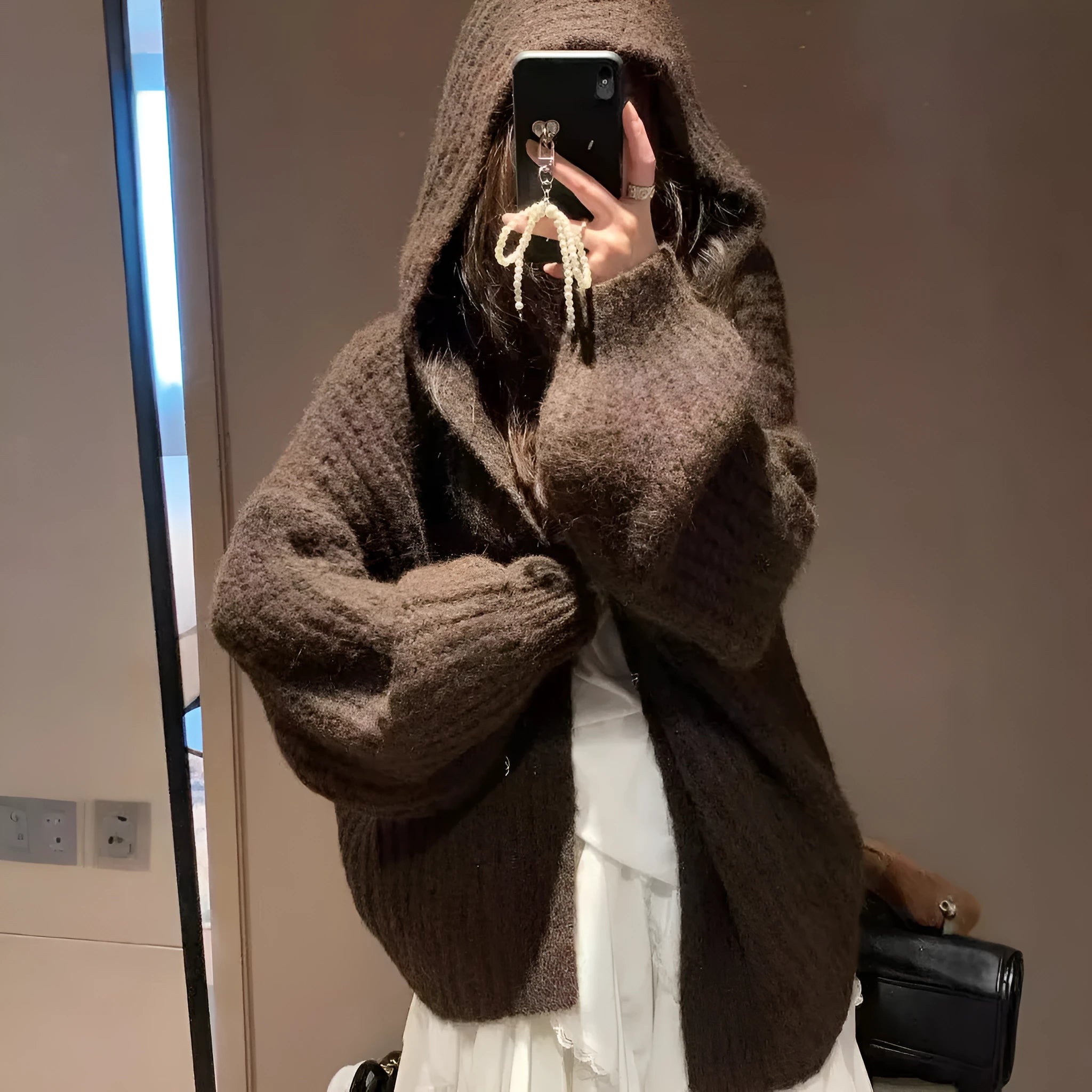 A woman's loose-fit hooded sweater cardigan in a thick fabric, shown in dark grey, brown, and milky white colour options.