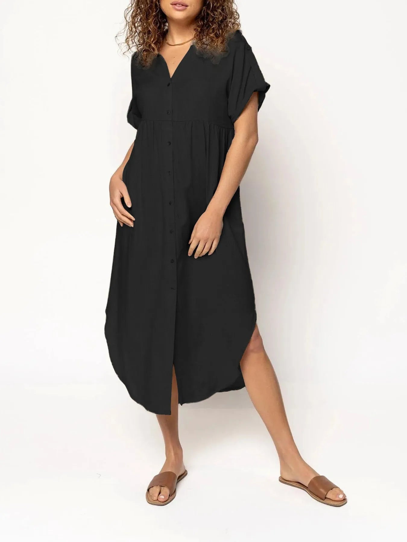A woman wearing a loose-fitting, mid-length apricot-coloured casual dress with a button-down front.