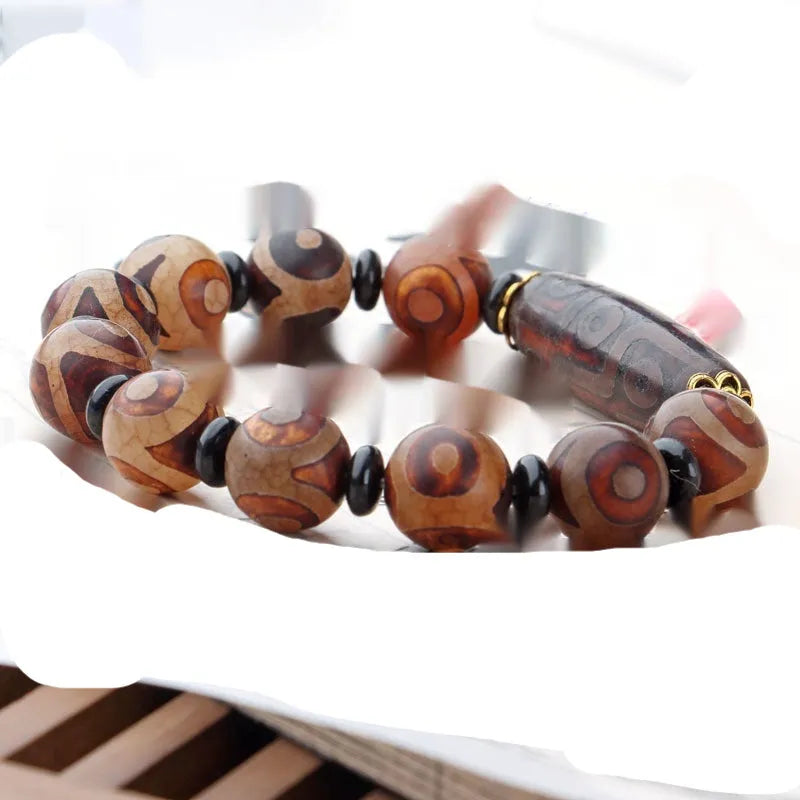 Distressed agate Tibetan bead bracelet with three-eye motifs and polished finish.