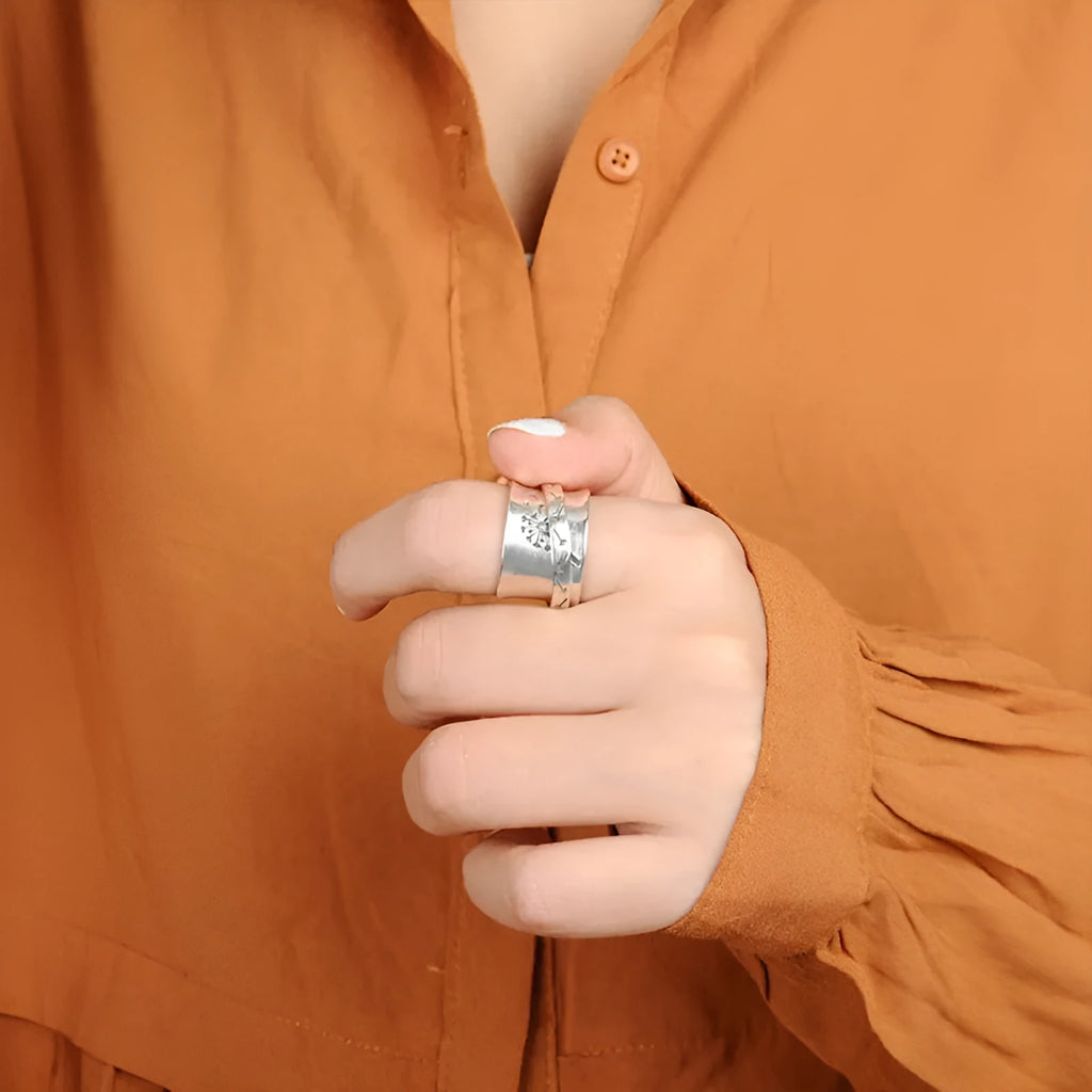 Silver coloured rotating flower fashion ring on a hand, showing adjustable band and floral design.