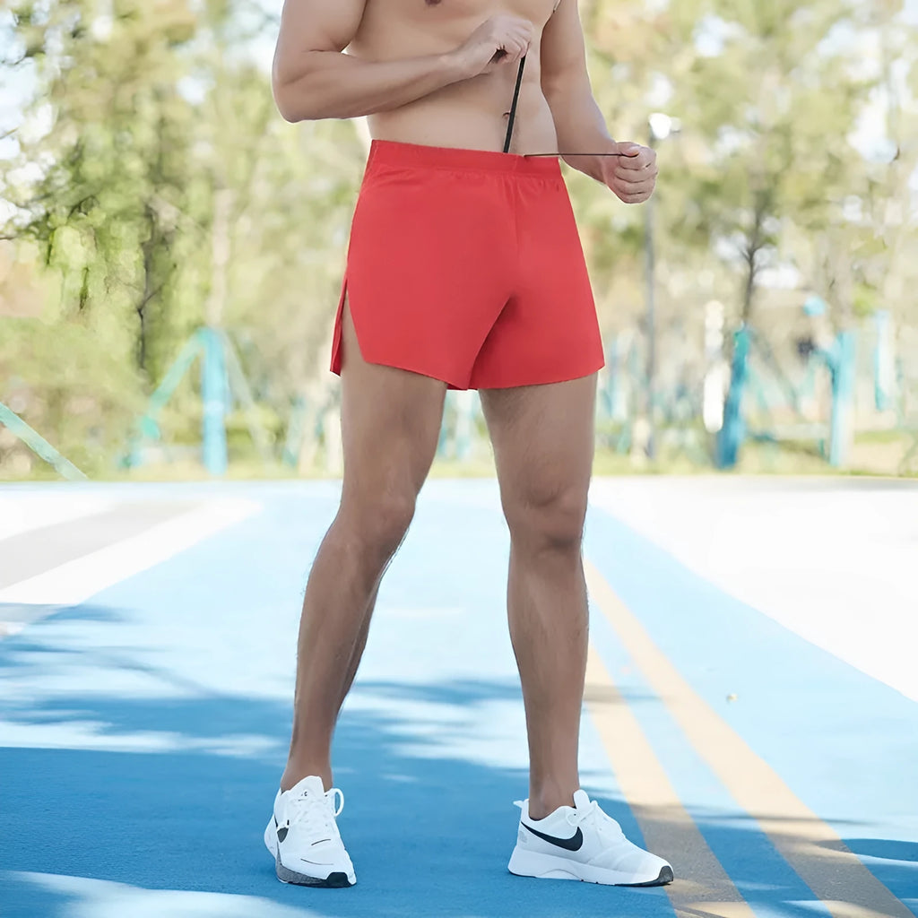 Men's red off-road running shorts with high waist and loose fit on a running trail.
