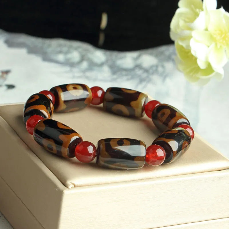 Distressed agate Tibetan bead bracelet with three-eye motifs and polished finish.