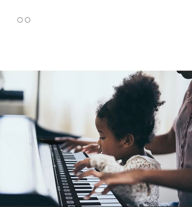 Portable black folding electronic keyboard rolled up next to its control panel and cable.