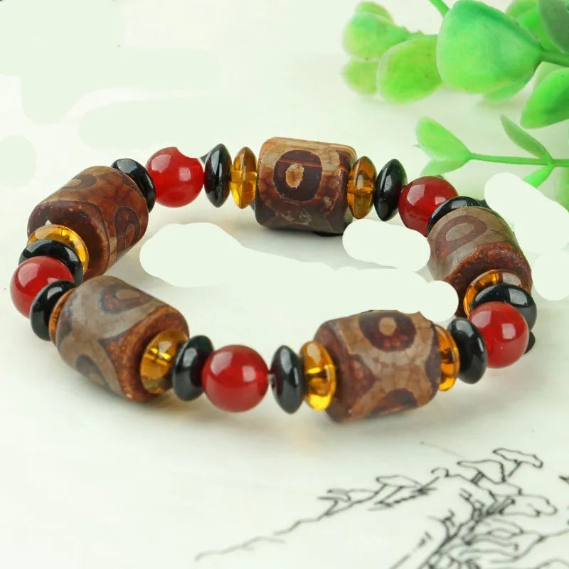 Distressed agate Tibetan bead bracelet with three-eye motifs and polished finish.
