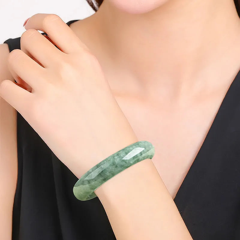 A simple dark pea green natural jade ring bracelet for women on a white background.