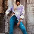 Lilac plaid print loose sweater with ribbed cuffs and collar on a hanger.