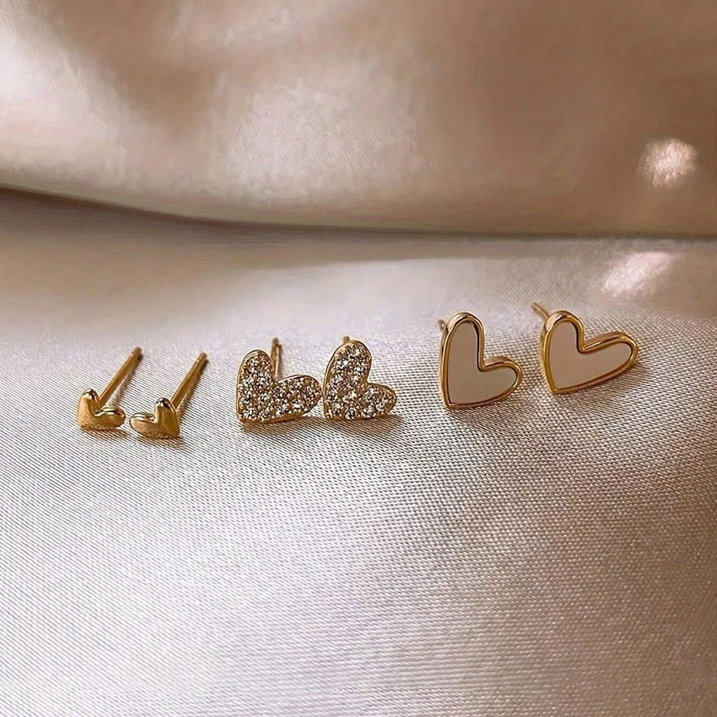 Three pairs of heart-shaped alloy earrings in gold, black, white and pink colours