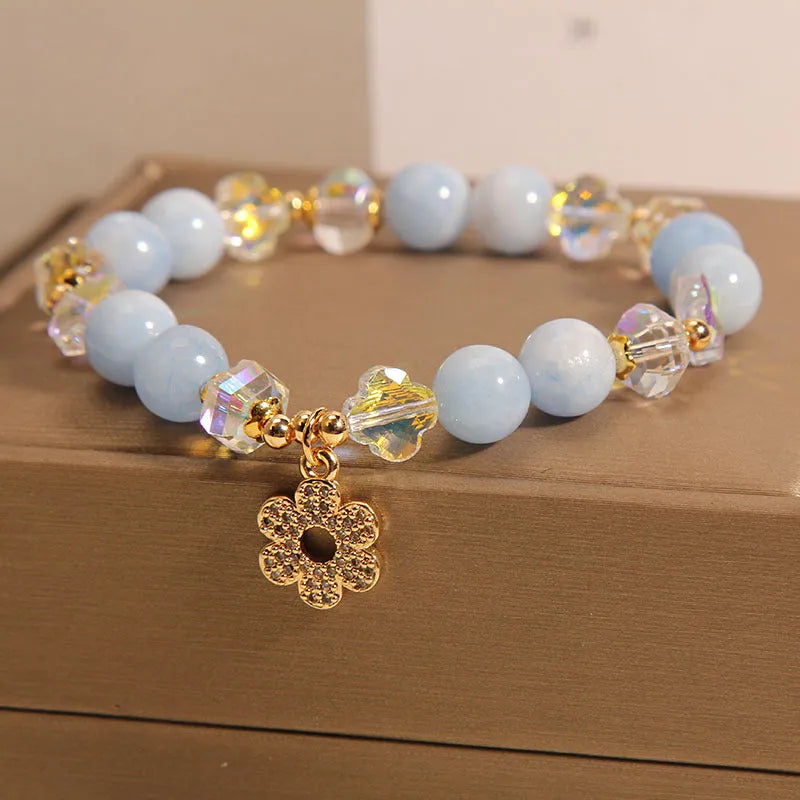 Women's aquamarine crystal bracelet with four-leaf clover charm and pearl accents on wrist