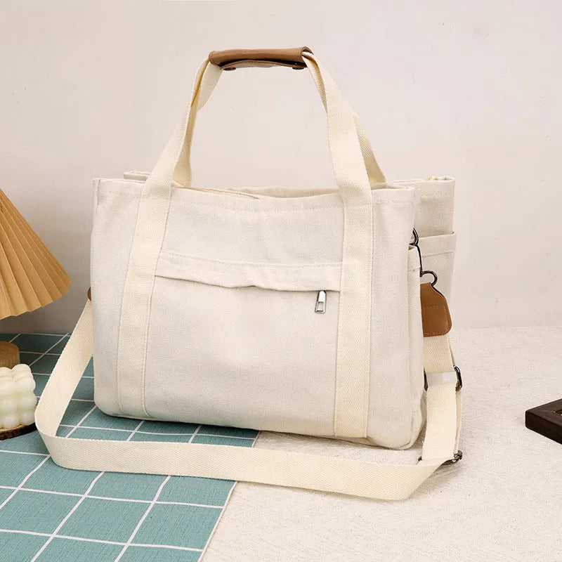 Large horizontal square canvas tote bag in army green with visible sewing lines and open zipper sides.