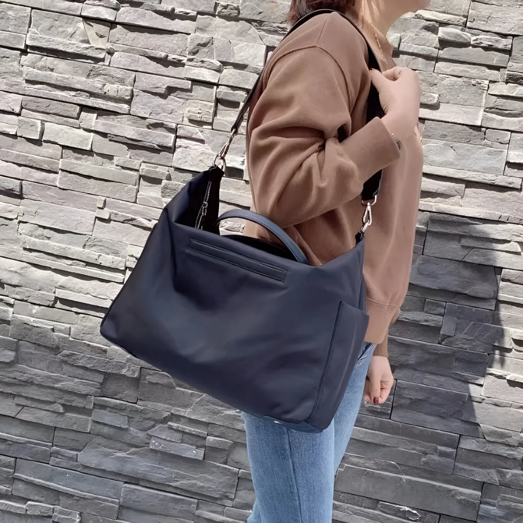 Black large capacity nylon waterproof shoulder bag with leather accents on a plain background.