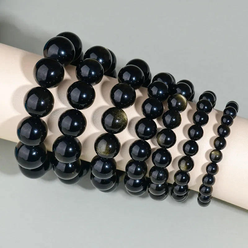 Hand-woven round obsidian crystal bracelet in ethnic style on a wrist, showing colour and bead size options.