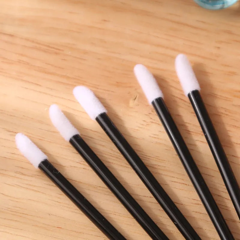 Pack of disposable flocked lip brush applicators with coloured handles on a white surface.