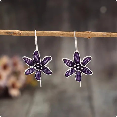A pair of simple purple flower-shaped alloy earrings for women on a white background.