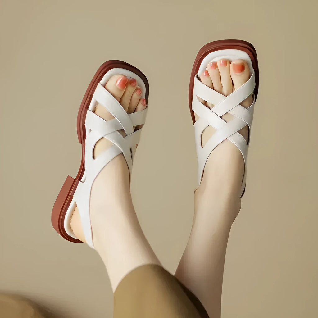 Women's glossy black patent leather sandals with a square toe and low heel on a rubber sole.