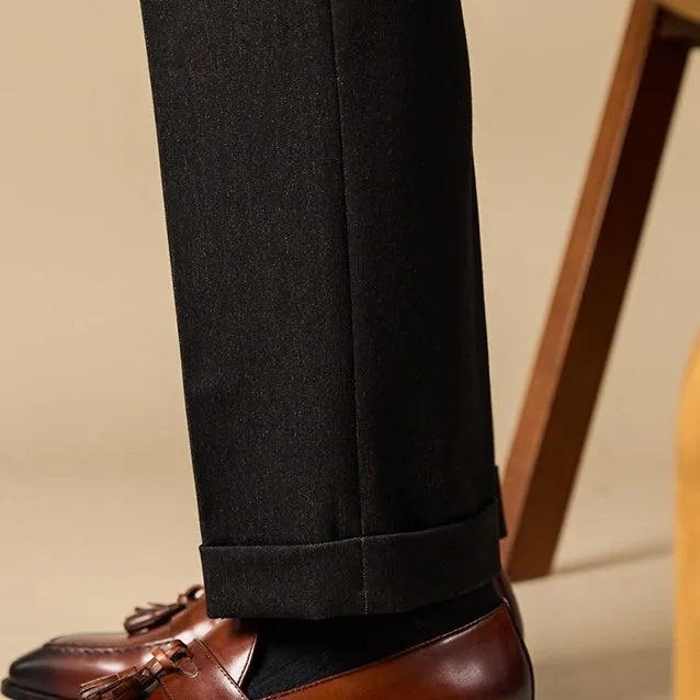 Men's black polished leather tassel loafers on a white background, side view showing rubber sole.