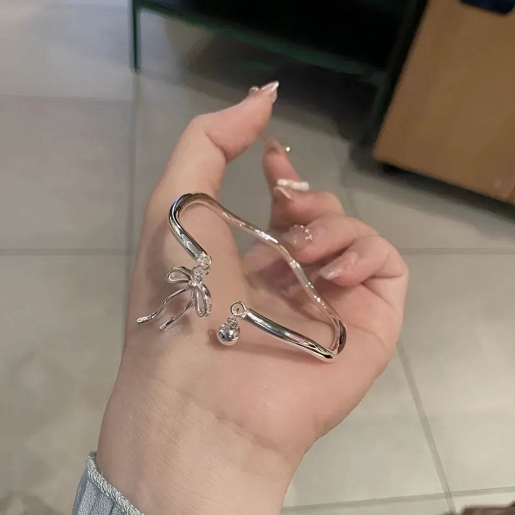 Silver bow adjustable bracelet with bell opening mechanism on wrist