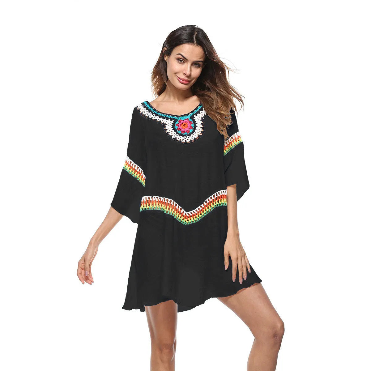 Female model wearing a crocheted ethnic style white sun protection cover-up on the beach.