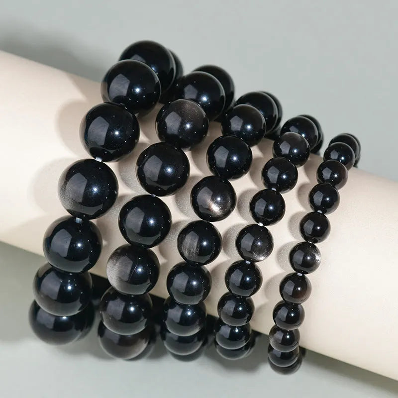 Hand-woven round obsidian crystal bracelet in ethnic style on a wrist, showing colour and bead size options.