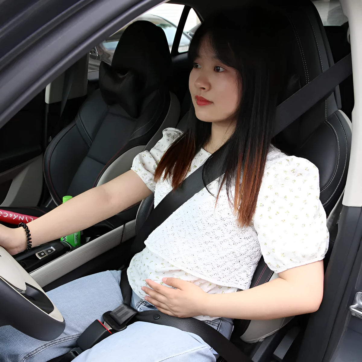 Adjustable black maternal car seat belt support with press buckle, shown wrapped around a vehicle seat belt.