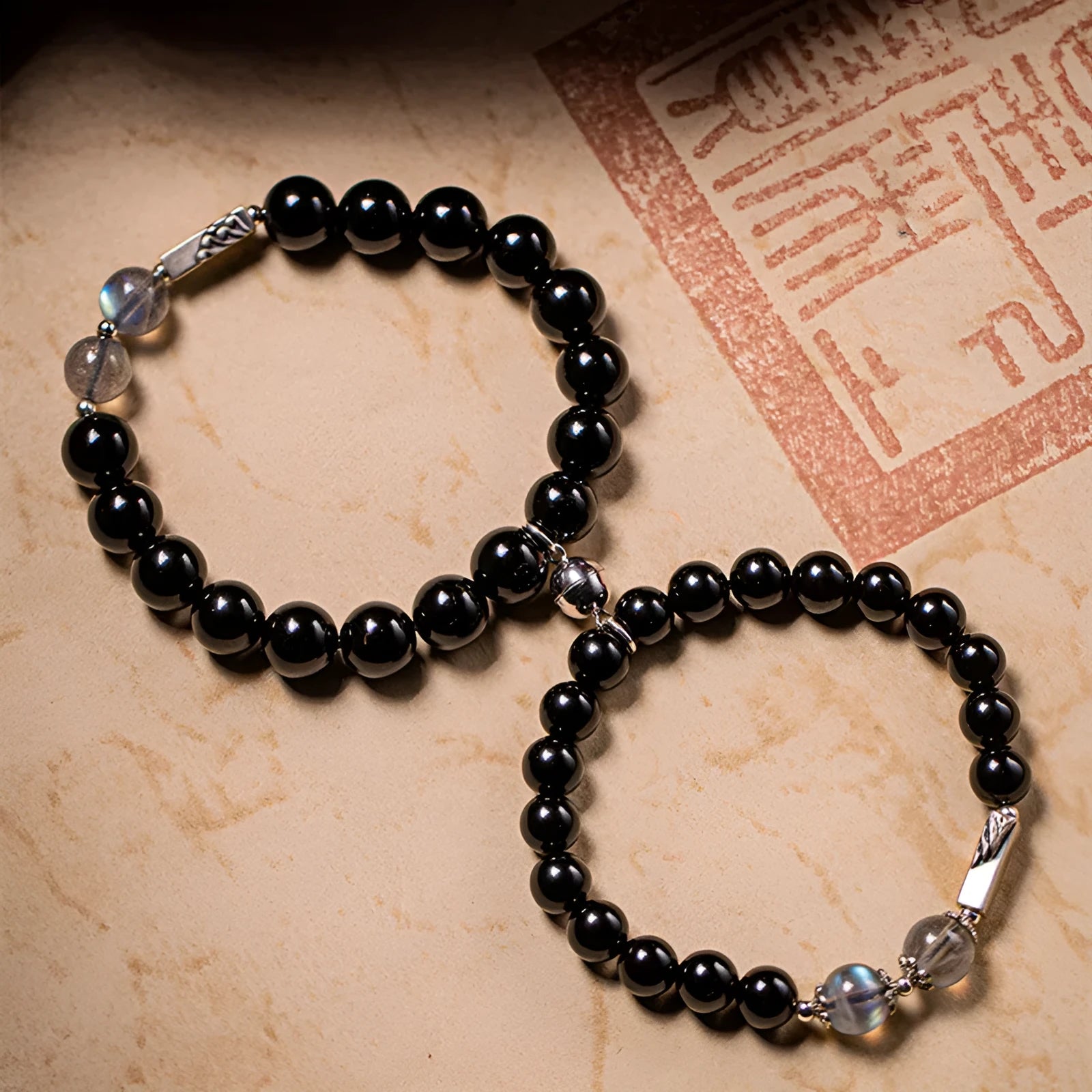 Obsidian Buddha beads couple bracelet set showing 8mm women's and 10mm men's sizing differences