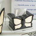 Ceramic butterfly vase and matching tissue box set on a living room table.