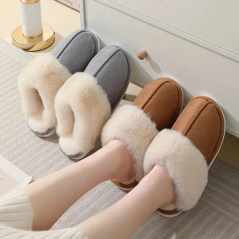 A pair of plush indoor slippers with a round toe, flat heel, and stitching detail, shown in one of five available colours.