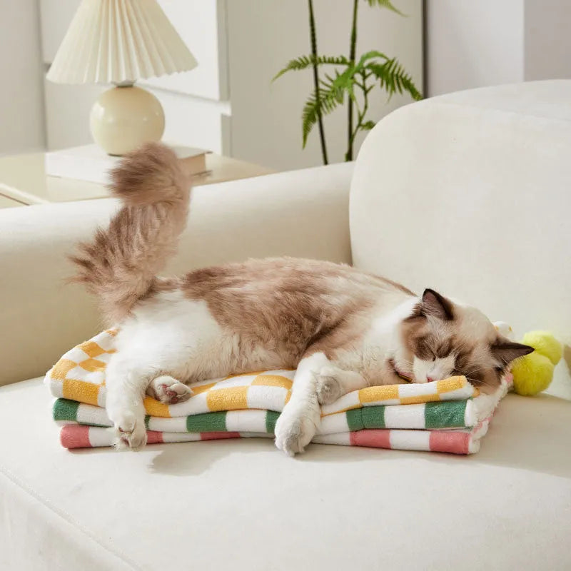 Plush pet blanket with bright plaid pattern and fur ball decorations for cats and dogs